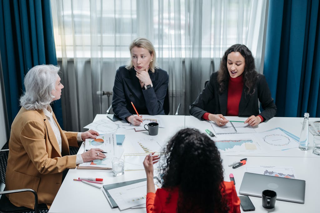 Four professional women engaged in a productive office meeting, discussing business plans.